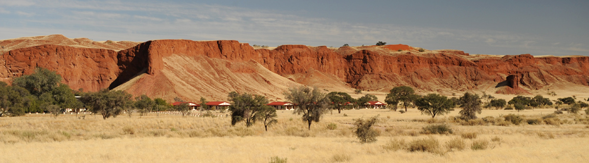 Namib Desert Lodge guest rooms spread along the base of fossilised red namib sand dunes near Sossusvlei Namibia