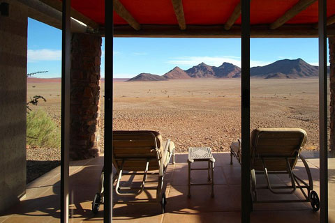 Two loungers occupy the verandah of a guest Villa overlooking the private andBeyond Sossusvlei Desert Reserve from inside one of the guest villas.